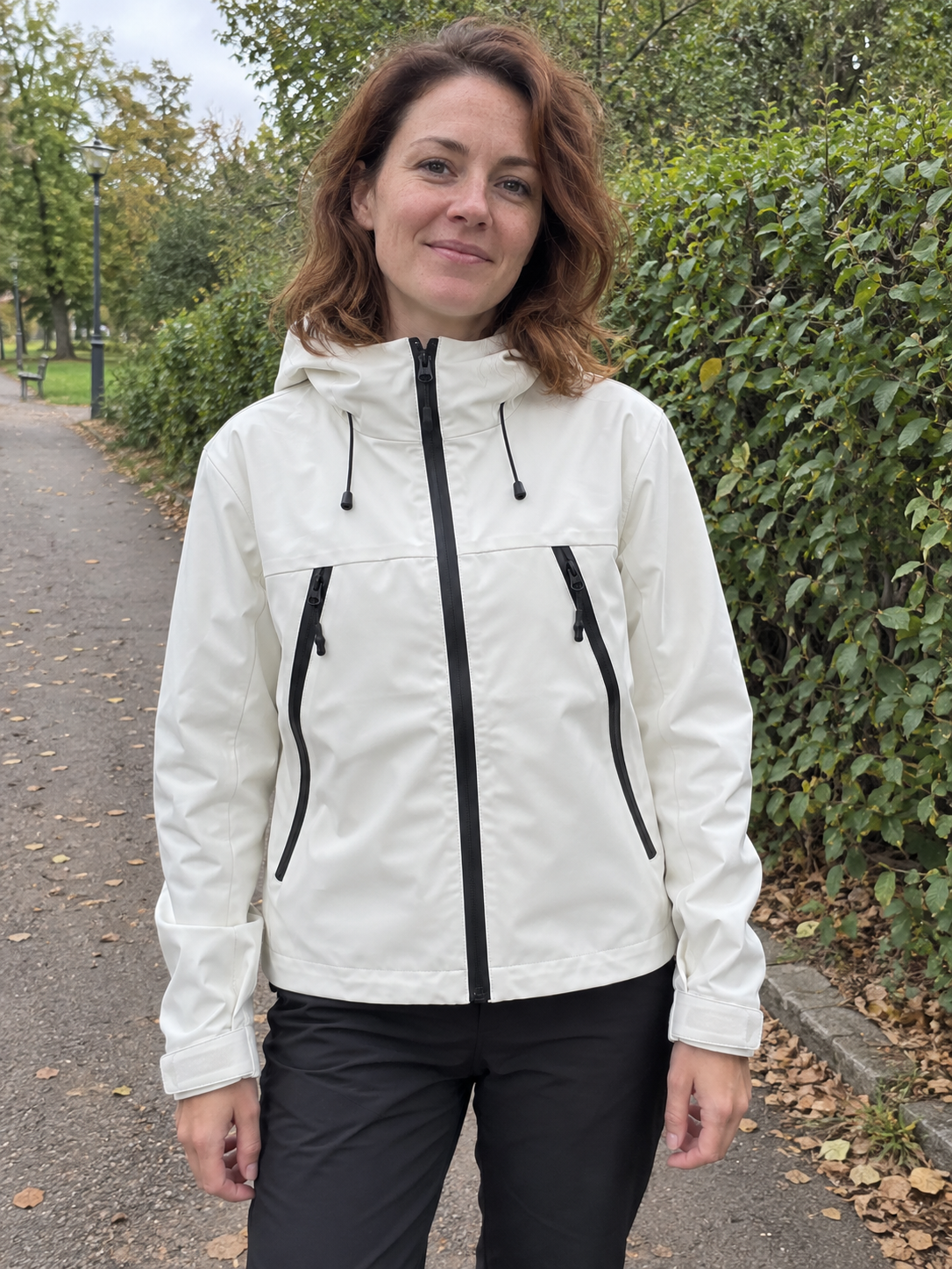 Woman in a white cropped jacket on a park path